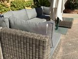 a wicker couch and chair on a patio with an umbrella