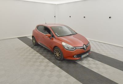 La voiture orange est garée dans le garage, sur le sol à damier.