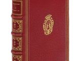 un vieux livre rouge aux tranches dorées, orné d'un emblème doré sur la couverture
