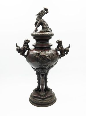 a bronze urn with a statue on top of it