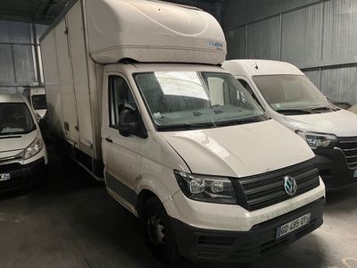 Trois fourgonnettes blanches sont garées dans un garage, avec d'autres fourgonnettes en arrière-plan.