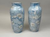 une paire de vases bleus ornés de fleurs blanches sur fond blanc