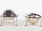 pair of silver plated chairs with legs and legs on a white surface