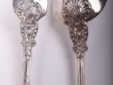 two silver spoons and a fork on a table