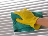 a person in yellow gloves cleaning a window with a green rag