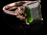 une bague en tourmaline verte et diamants posée sur un fond noir