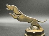 sculpture en bronze représentant un chien sautant par-dessus une balle, posée sur un socle