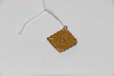 une petite fleur en or suspendue à un fil, posée sur une assiette blanche