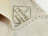 someone is holding a pair of white shoes with a label on it