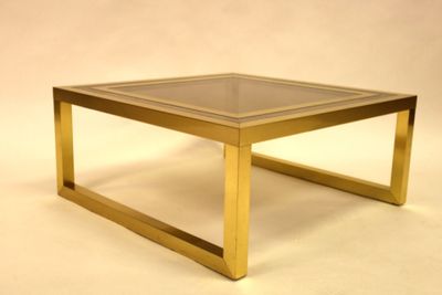 a glass top coffee table with a gold frame