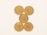 four gold coins sitting on top of each other on a white surface