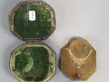 a small green box with a gold lid and a small green box with a gold lid sitting on a white surface