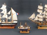 trois maquettes de bateaux exposées sur une table