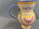 a yellow and blue vase sitting on a gray surface