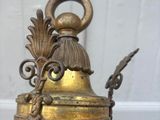 brass plated candle holder with a bell and tassels on it