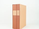 a brown book sitting on top of a white table next to a white wall