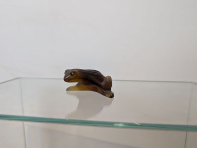 une petite figurine représentant un cheval, posée sur une étagère en verre