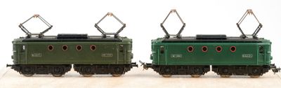 two green trains sitting side by side on a wooden table
