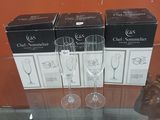 three wine glasses sitting on top of a glass table next to boxes of wine
