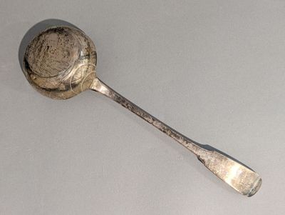 une cuillère en argent avec un manche de cuillère sur une table