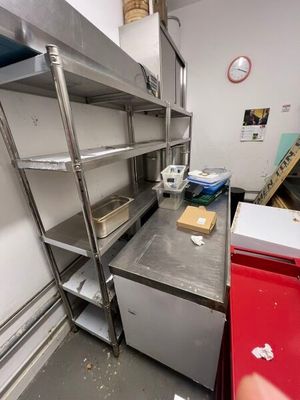 a kitchen with a lot of shelves and a red trash can