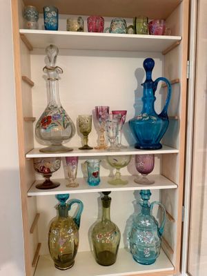 many glass vases on the shelves in this cabinet