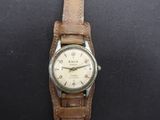 une image représentant une montre-bracelet avec un bracelet en cuir posée sur une surface noire