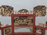 a red and gold oriental screen with pictures of people on it