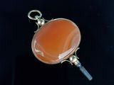 a close up of a pendant with an orange stone in it