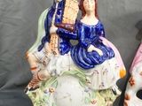 two figurines of people sitting on top of a skull