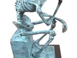 statue représentant un squelette assis sur un bloc, un marteau à la main