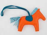 une décoration en forme de cheval orange et bleu suspendue sur un fond blanc