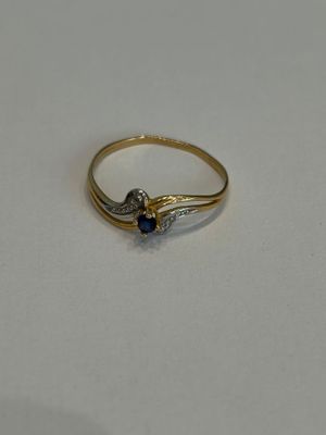gros plan d'une bague en or avec une pierre bleue
