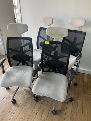 Trois chaises de bureau sont posées sur un parquet en bois massif, devant un mur blanc.