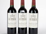 trois bouteilles de vin rouge posées côte à côte sur une table