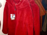 several red coats hanging on a rack in a room