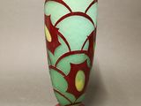 a red vase with a green and yellow design on it