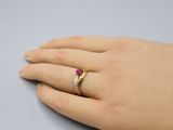 la main de quelqu'un, à laquelle est passée une bague en or sertie d'une pierre rouge