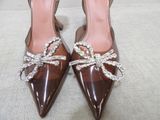 the woman is wearing brown shoes with a bow on the toe