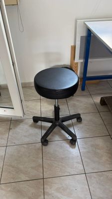 un tabouret noir posé au milieu d'un sol carrelé