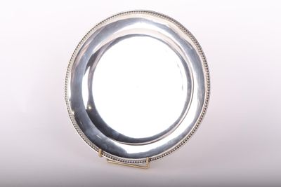 assiette en argent plaqué avec un bord festonné sur fond blanc