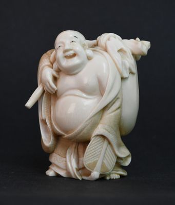 une statue blanche représentant un Bouddha souriant tenant un bâton