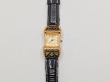 a gold plated wrist watch with a black leather strap