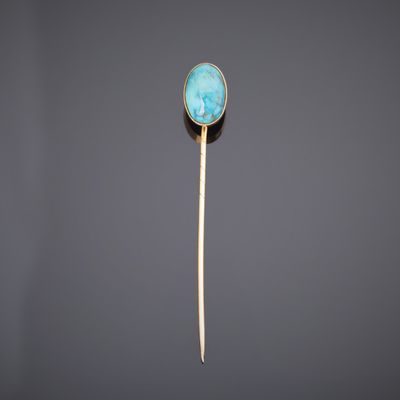 une broche en or et en pierre turquoise montée sur une tige