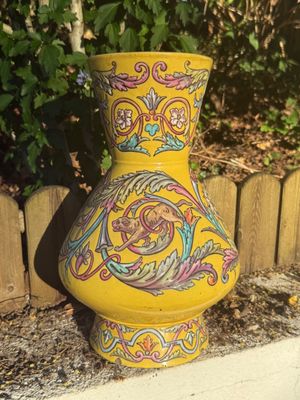 brightly colored vase sitting in front of a wooden fence in a garden
