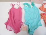 three swimsuits and a bag on a table