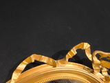 a mirror with a gold frame on a black surface