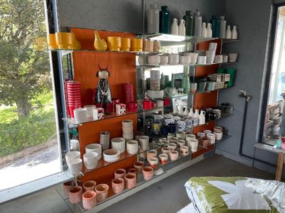 a room with a shelf full of pottery and pots