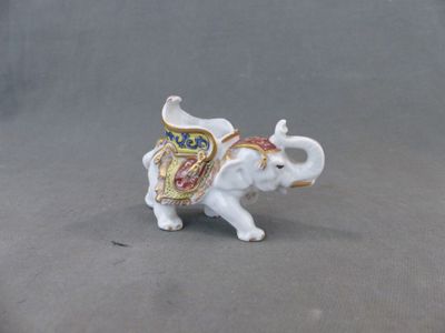 une petite figurine représentant un éléphant posée sur une surface grise