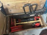une caisse en bois posée par terre, contenant des outils